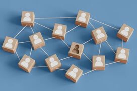 Wooden blocks connected by strings representing team members, with one block showing two figures symbolizing staffing issues and team imbalance.