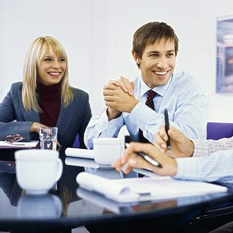 Two co-workers smiling during a meeting.