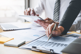 Business professionals reviewing workforce data on a tablet and printed charts, analyzing contingent labor metrics during a meeting.